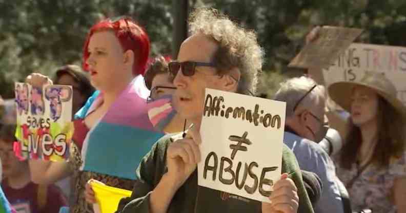 A person holds up a sign that reads 'Affirmation ≠ abuse' in protest of Texas officials investigating the families of trans youth for 'child abuse'