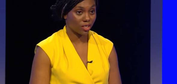Kemi Badenoch wears a bright yellow outfit as she speaks at a podium during a Tory leadership election debate