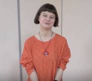 Yulia Tsvetkova, an artist and LGBTQ+ activist, wears an orange outfit and long necklace as she speaks to someone off camera