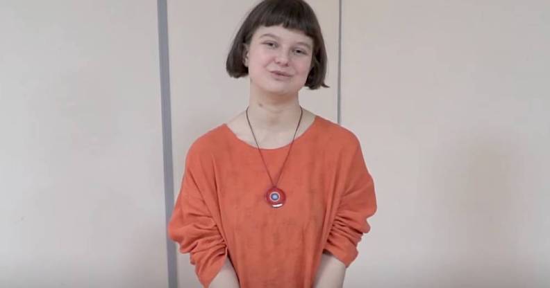 Yulia Tsvetkova, an artist and LGBTQ+ activist, wears an orange outfit and long necklace as she speaks to someone off camera