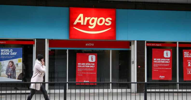 A person communicating on a mobile phone walks past a branch of Argos