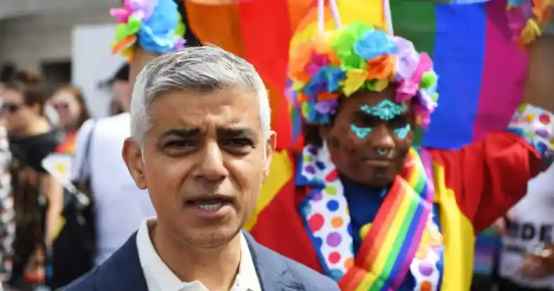 Sadiq Khan, behind him in a person holding a rainbow Pride flag