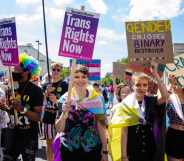 People marching in London Trans+ Pride with placards reading: 'Trans Rights Now' and 'Gender ejoyer binary destroyer'