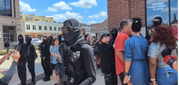 A group of armed counter-protestors stand around the Anderson Distillery and Grill.