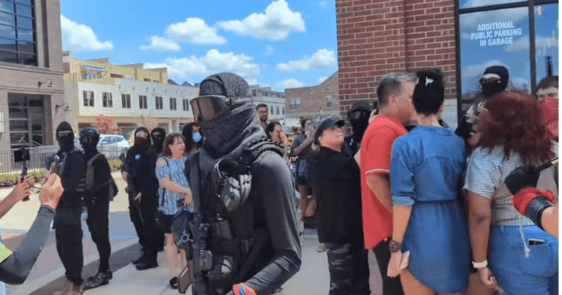 A group of armed counter-protestors stand around the Anderson Distillery and Grill.