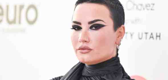 Demi Lovato wears dark clothing and matching dark eye makeup as they pose for the camera