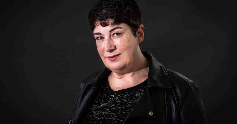 Joanne Harris wears a dark shirt and jacket while standing in front of a dark background