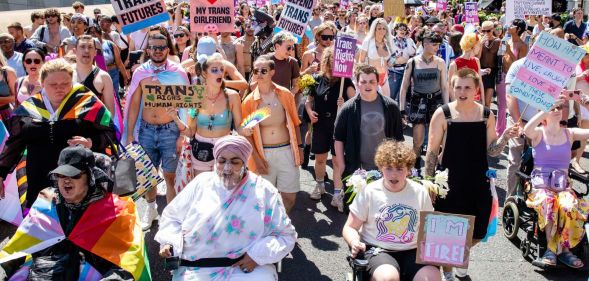 Several people gather for London Trans+ Pride holding up signs in support of the trans community