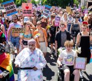 Several people gather for London Trans+ Pride holding up signs in support of the trans community