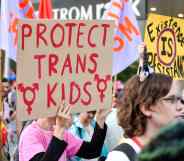 An activist raises a placard saying "protect trans kids" during a protest.