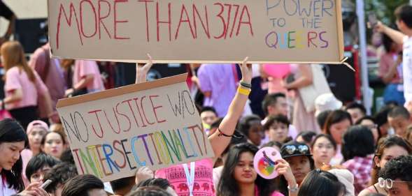 Protesters hold signs at Singapore's Pink Dot event reading 'more than 377a'
