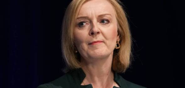 Liz Truss wears a dark green top as she stares somewhere off camera