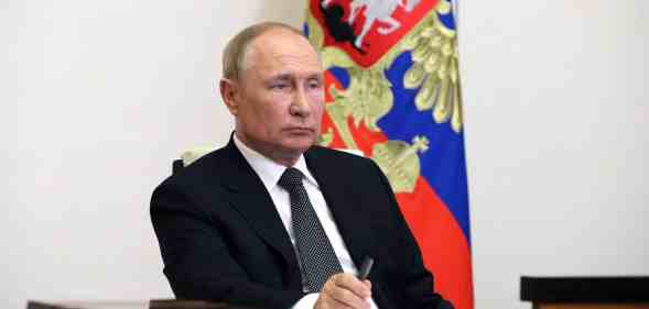 Vladimir Putin sits at a desk