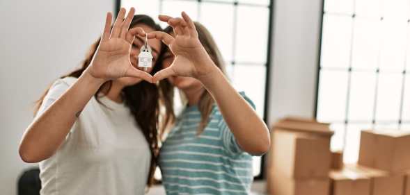 This stock photo shows a lesbian couple hold keys to a new home.