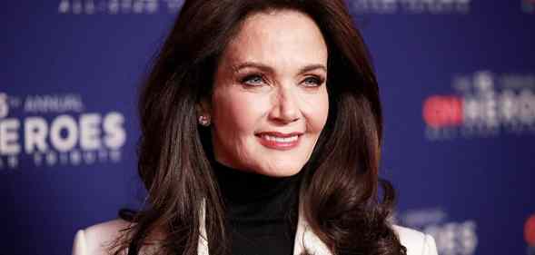 Lynda Carter wearing a grey suit and black turtleneck on a red carpet.