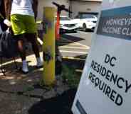 People wait in line for a monkeypox vaccine as a sign outside reads 'Monkeypox vaccine clinic DC residency required'