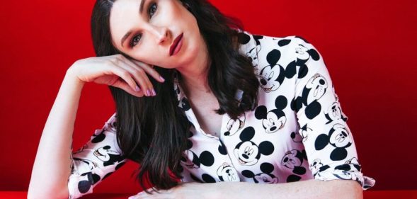 Juno Dawson tilting her head with a red background.