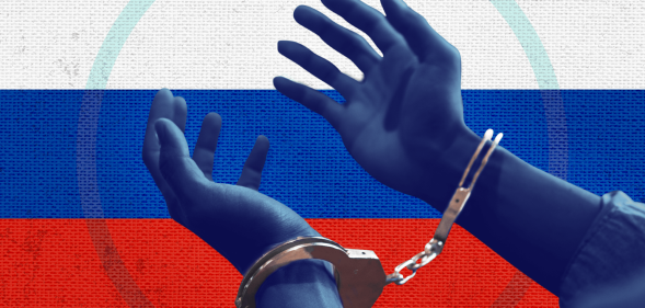 A colourised photo of blue hands in handcuffs in front of the Russian flag