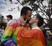 Two people wearing rainbow colours kiss in a park in Bogota, Columbia during a LGBTQ+ protest