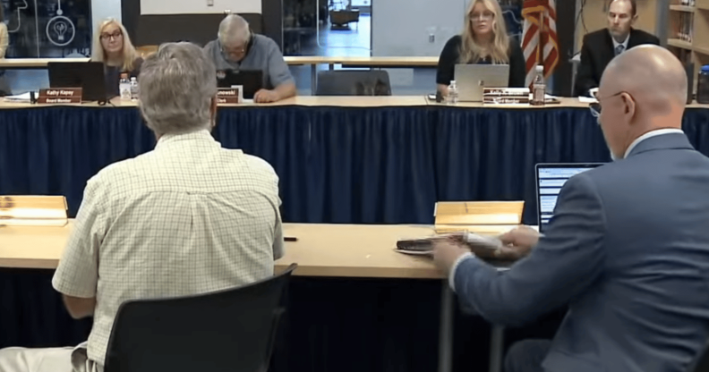 A row of board members sit to discuss the board agenda.
