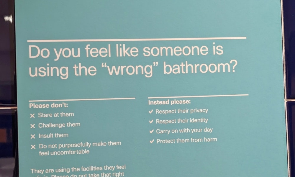 In this photograph, a sign says what to do if someone feels like there's a person in the 'wrong' bathroom