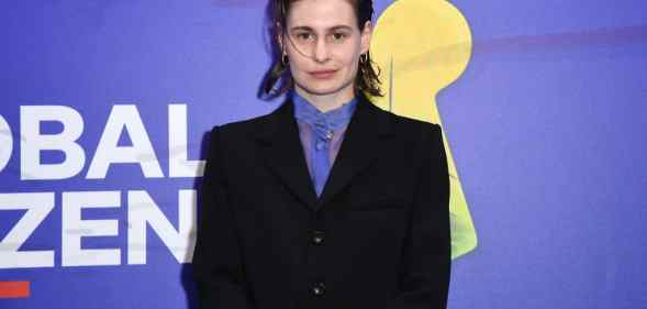 Photo of Redcar in a black suit with sheer purple shirt, against a purple backdrop