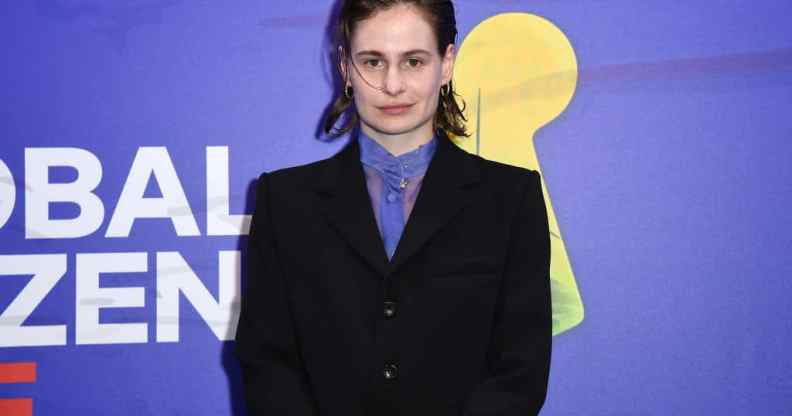 Photo of Redcar in a black suit with sheer purple shirt, against a purple backdrop