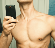 A topless man taking a mirror selfie, his face cropped out