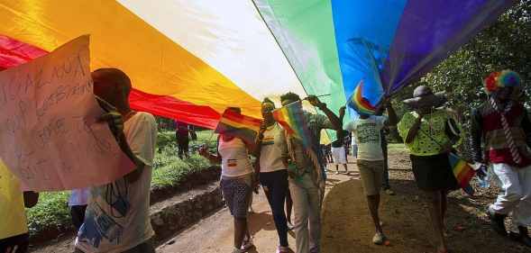 People walk underneath a Pride flag