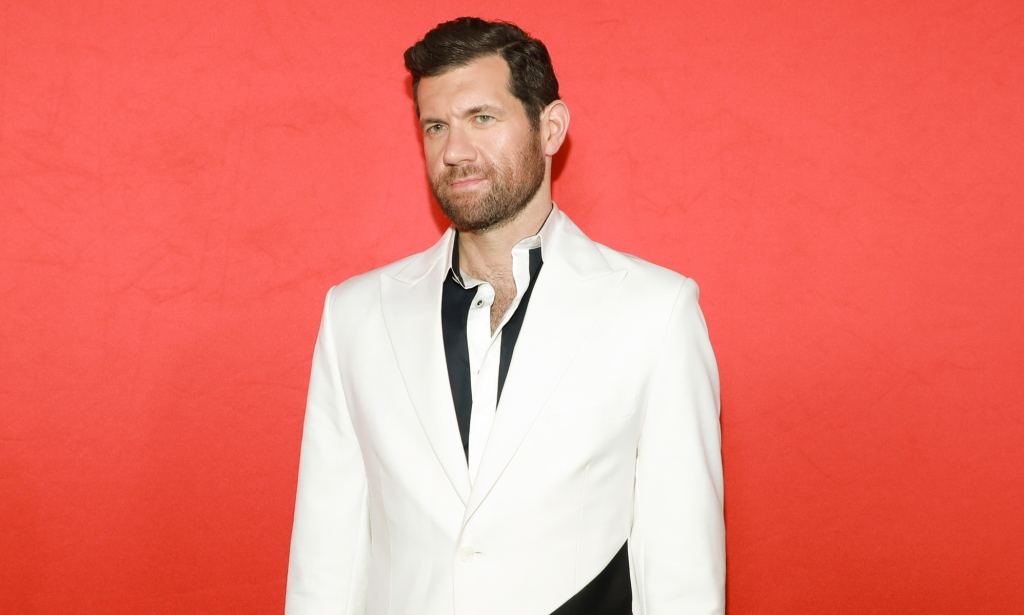 Promotional still of comedian Billy Eichner wearing a black shirt and white suit jacket.