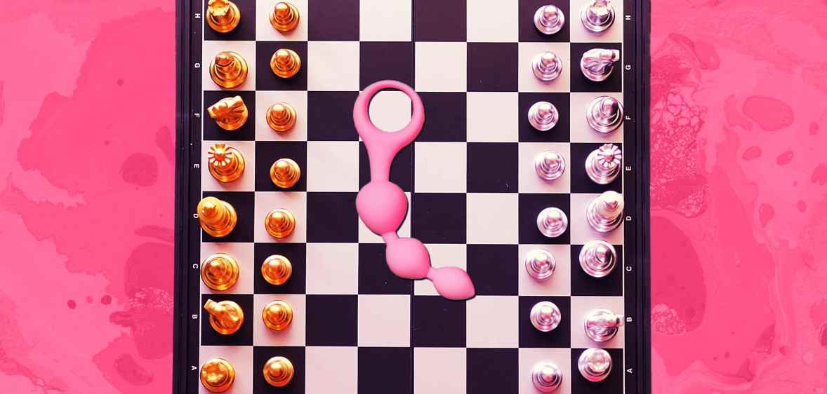 An image of a chess board against a pink background with anal beads in the centre of the board.