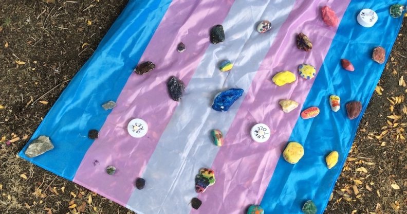 A flag laid out with stones at a vigil for the young trans man attacked during Pride celebrations