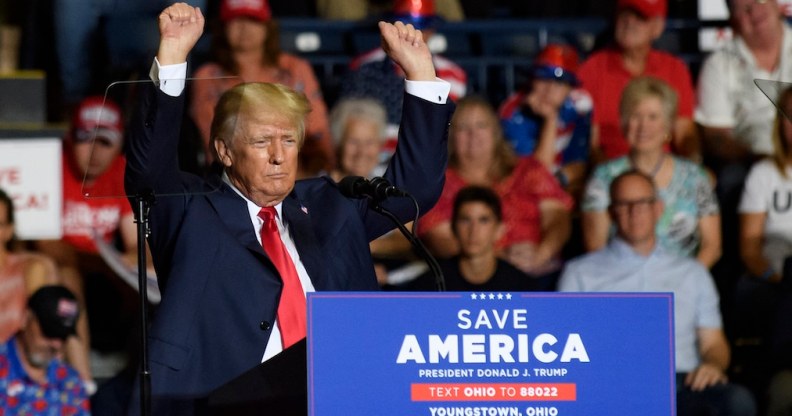 Donald Trump waves his small arms in the air at a Save America Rally