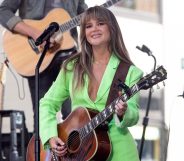 Maren Morris in a green suit playing the guitar.
