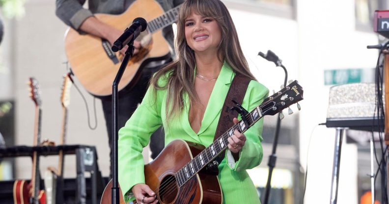 Maren Morris in a green suit playing the guitar.