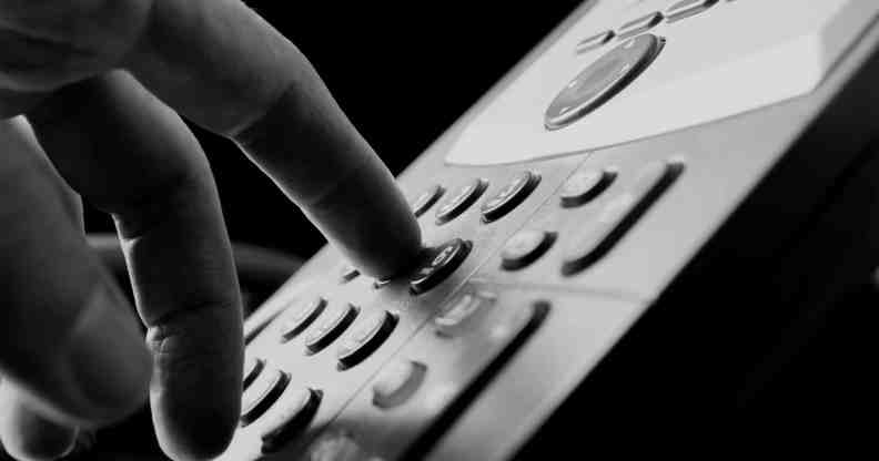 Close up of the fingers of a man dialing out on a land line telephone pressing the number keys on the keypad in a communications concept.