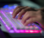 A person types on a white keyboard with LEDs lighting it up.