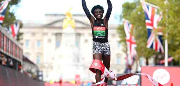 Runner Joyciline Jepkosgei holds her arms aloft as she crosses the finish line in front of Buckingham Palace