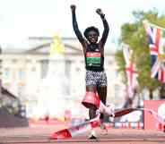 Runner Joyciline Jepkosgei holds her arms aloft as she crosses the finish line in front of Buckingham Palace