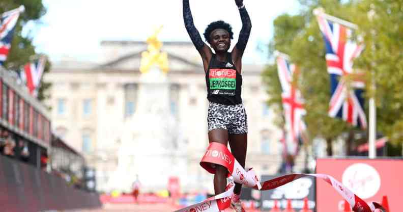 Runner Joyciline Jepkosgei holds her arms aloft as she crosses the finish line in front of Buckingham Palace