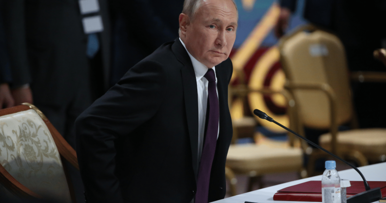 Vladimir Putin taking a seat during a political address
