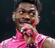 Lil Nas X wears a pink outfit as he sings into a microphone during a performance