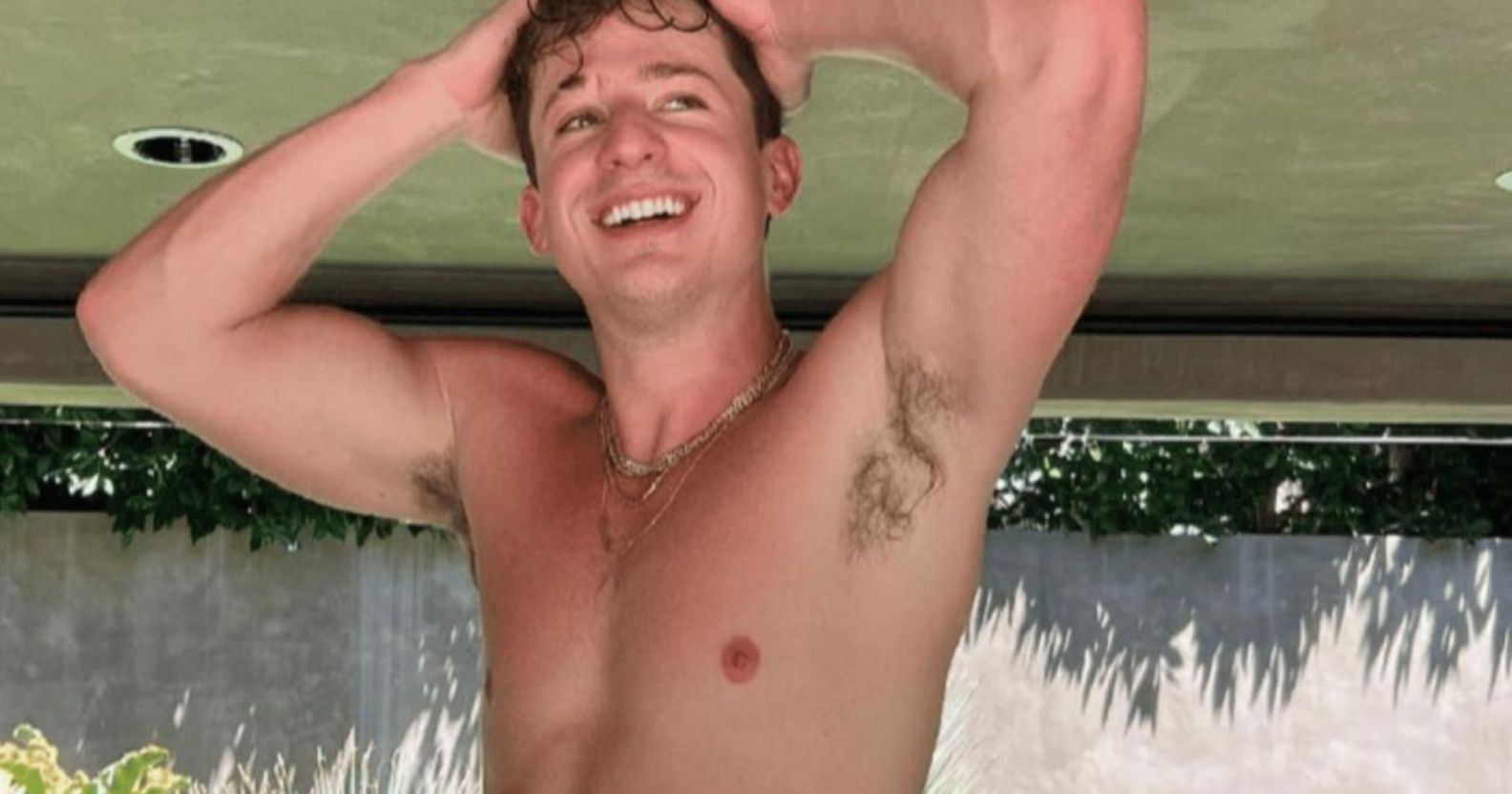 Charlie Puth, topless, with his arms above his head