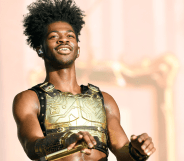 Lil Nas X wears a golden plated top as he performs on stage during a concert