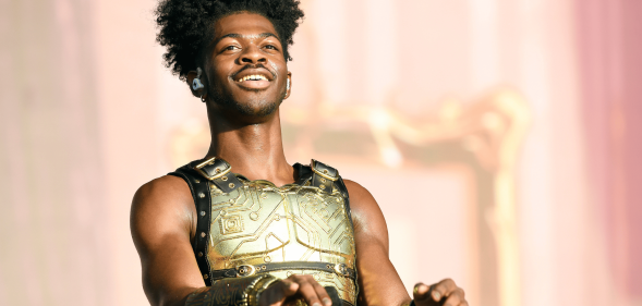 Lil Nas X wears a golden plated top as he performs on stage during a concert