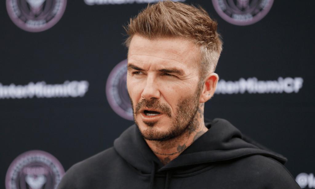 David Beckham wears a dark hooded sweatshirt as he speaks to someone off camera