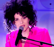 Jordan Gray wears a pink suit as she sings into a microphone during her Channel 4 Friday Night live performance