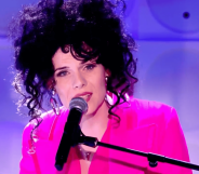Jordan Gray wears a pink suit as she sings into a microphone during her Channel 4 Friday Night live performance