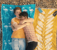Heartstopper characters Nick and Charlie hold each other as they enjoy a day at the beach in an episode of the Netflix series