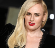 Rebel Wilson wears a black dress with her blonde hair styled over one shoulder